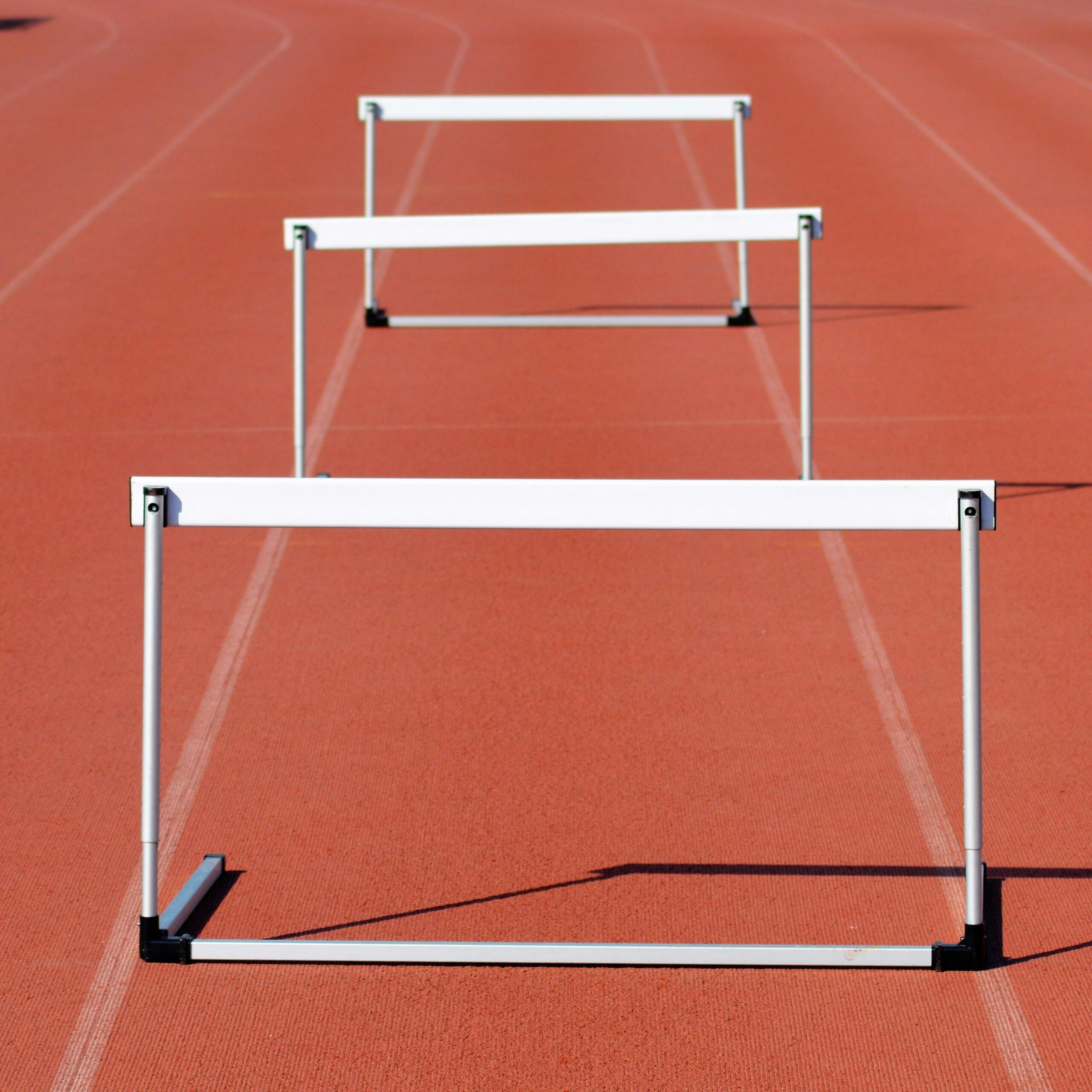 Three hurdles on a running track, illustrating the hurdles of mastering social media